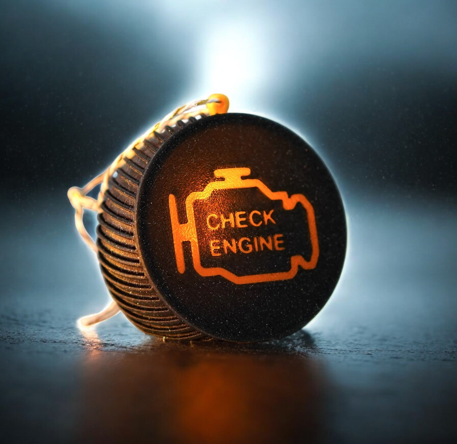 Weihnachtskugel "Check Engine" von Dreizack – schwarze Kugel mit orangem Kontrollleuchtensymbol, aus nachhaltigem PLA gefertigt, mit Platz für LED-Kerze, 6,5 cm Durchmesser. Perfekte Deko für Autoliebhaber.