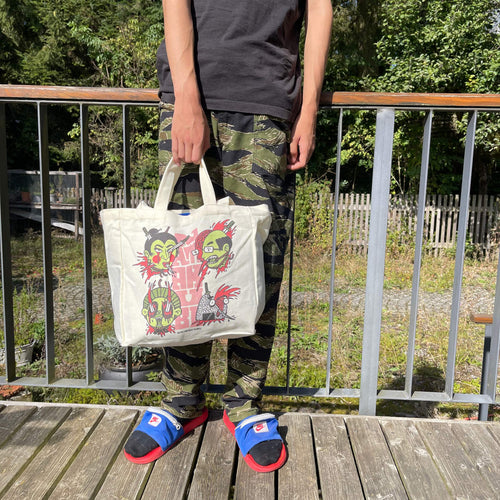 „Namakubi“ Tote Bag von Heldbergs Games mit vier ikonischen Köpfen, aus 16-Unzen-Baumwolle. Maße 32 x 33 x 16 cm, mit Magnetverschluss und Innentasche. Japanisches Design trifft auf praktischen Stil.