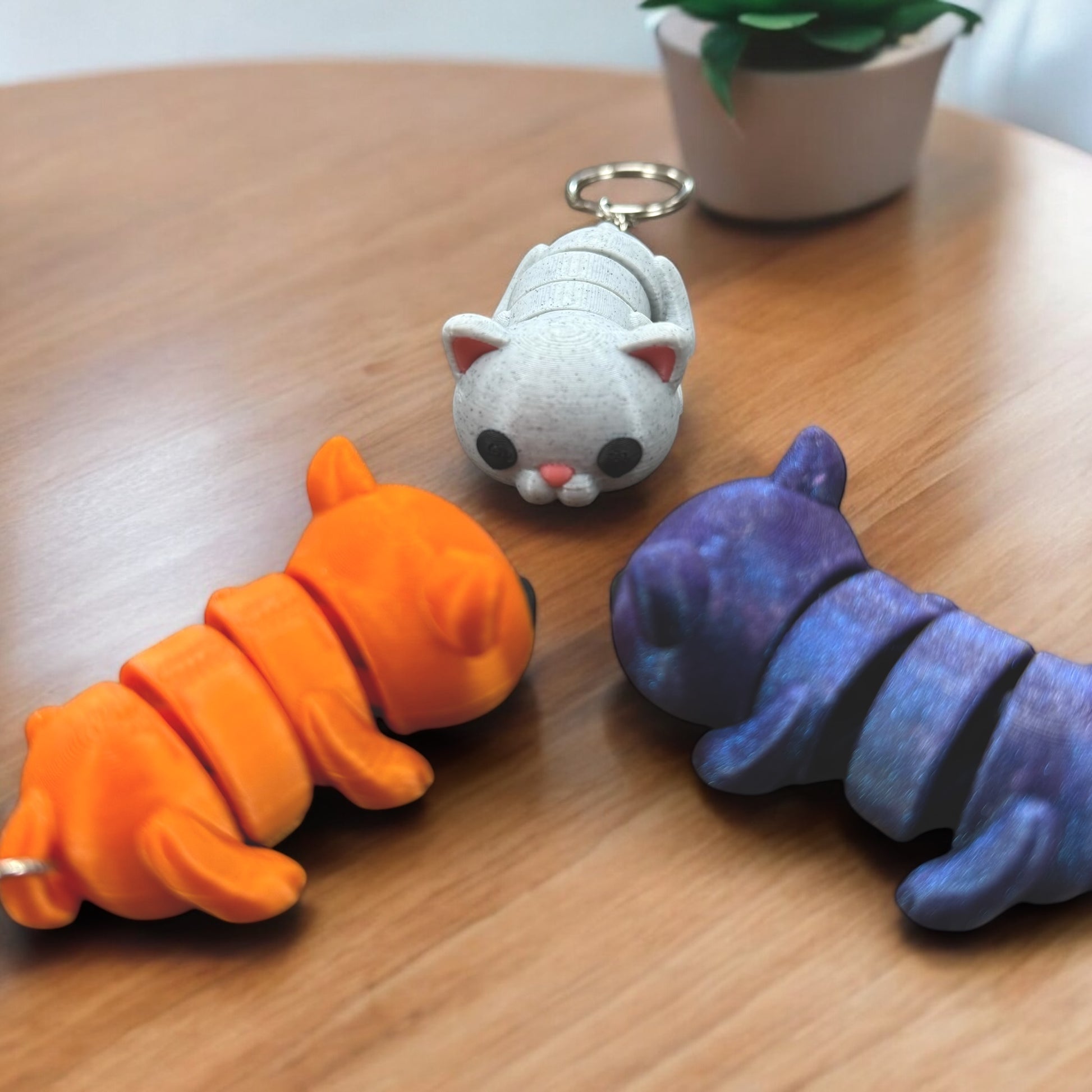 Schlüsselanhänger "Flexi-Katze" von Dreizack 3D-Druck: Bewegliche Katze aus nachhaltigem PLA in Farben wie Orange, Spacekitty (Blau-Violett-Verlauf) oder Marmor-Weiß, mit Edelstahl-Anhänger. Handgefertigt in Wien.