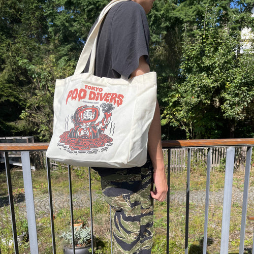 „Tokyo Poo Divers“ Tote Bag von Heldbergs Games, aus 16-Unzen-Baumwolle. Maße 32 x 33 x 16 cm, mit Magnetverschluss und Innentasche. Freches Design für urbane Legenden.