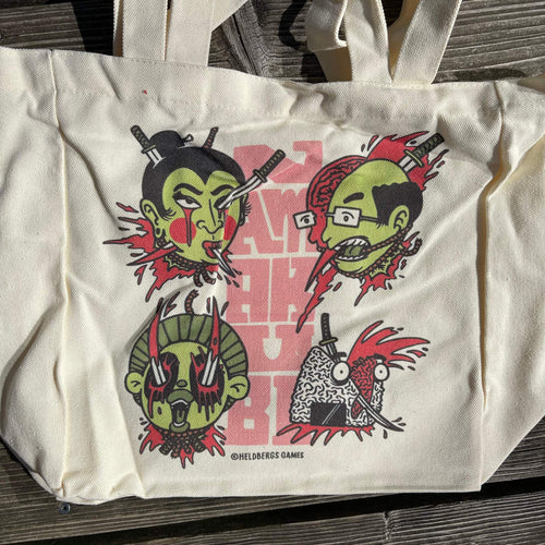 „Namakubi“ Tote Bag von Heldbergs Games mit vier ikonischen Köpfen, aus 16-Unzen-Baumwolle. Maße 32 x 33 x 16 cm, mit Magnetverschluss und Innentasche. Japanisches Design trifft auf praktischen Stil.