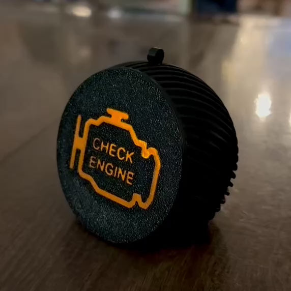 Weihnachtskugel "Check Engine" von Dreizack – schwarze Kugel mit orangem Kontrollleuchtensymbol, aus nachhaltigem PLA gefertigt, mit Platz für LED-Kerze, 6,5 cm Durchmesser. Perfekte Deko für Autoliebhaber.